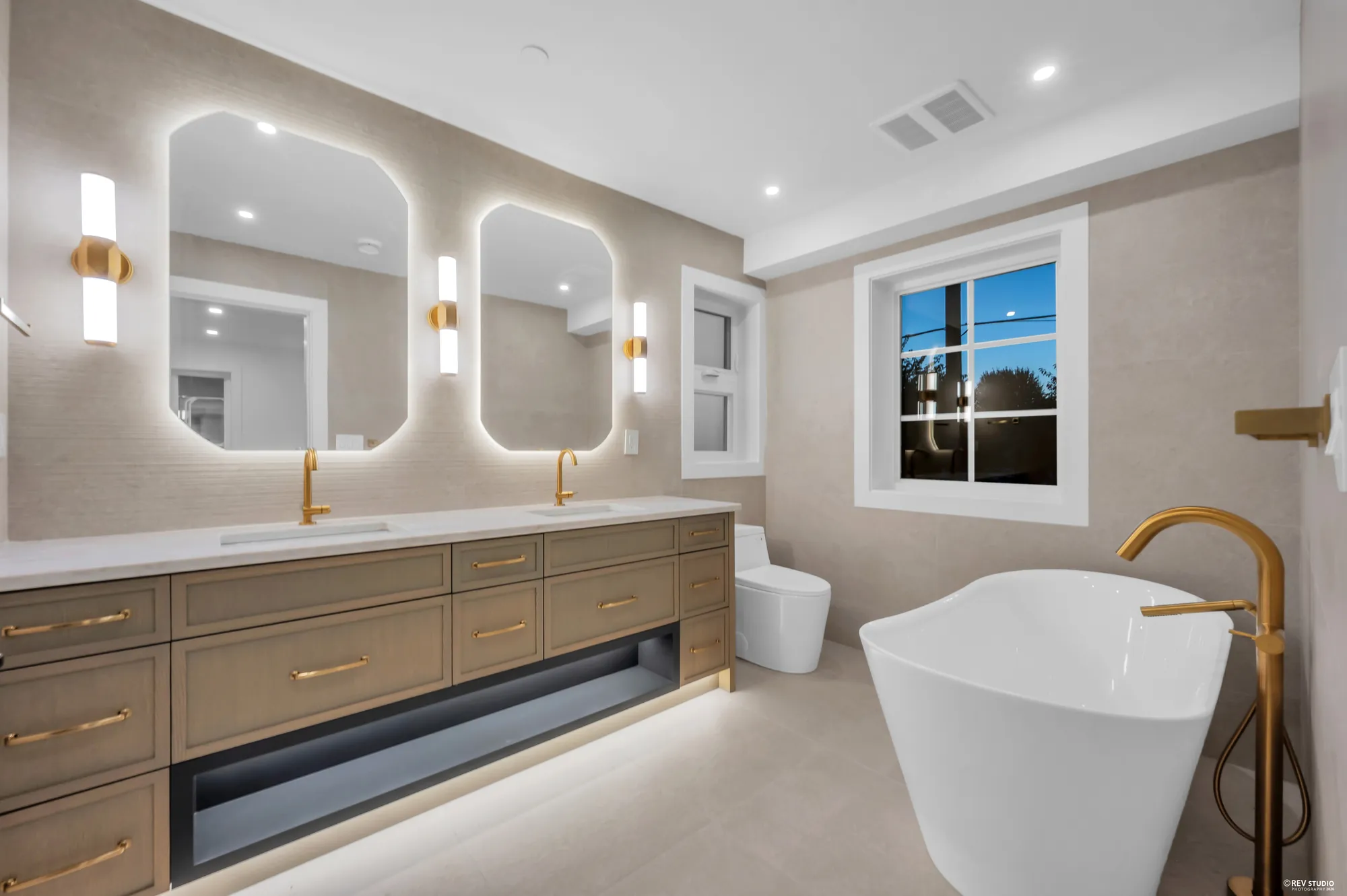 Bathroom with a freestanding tub, double vanity and backlit mirrors