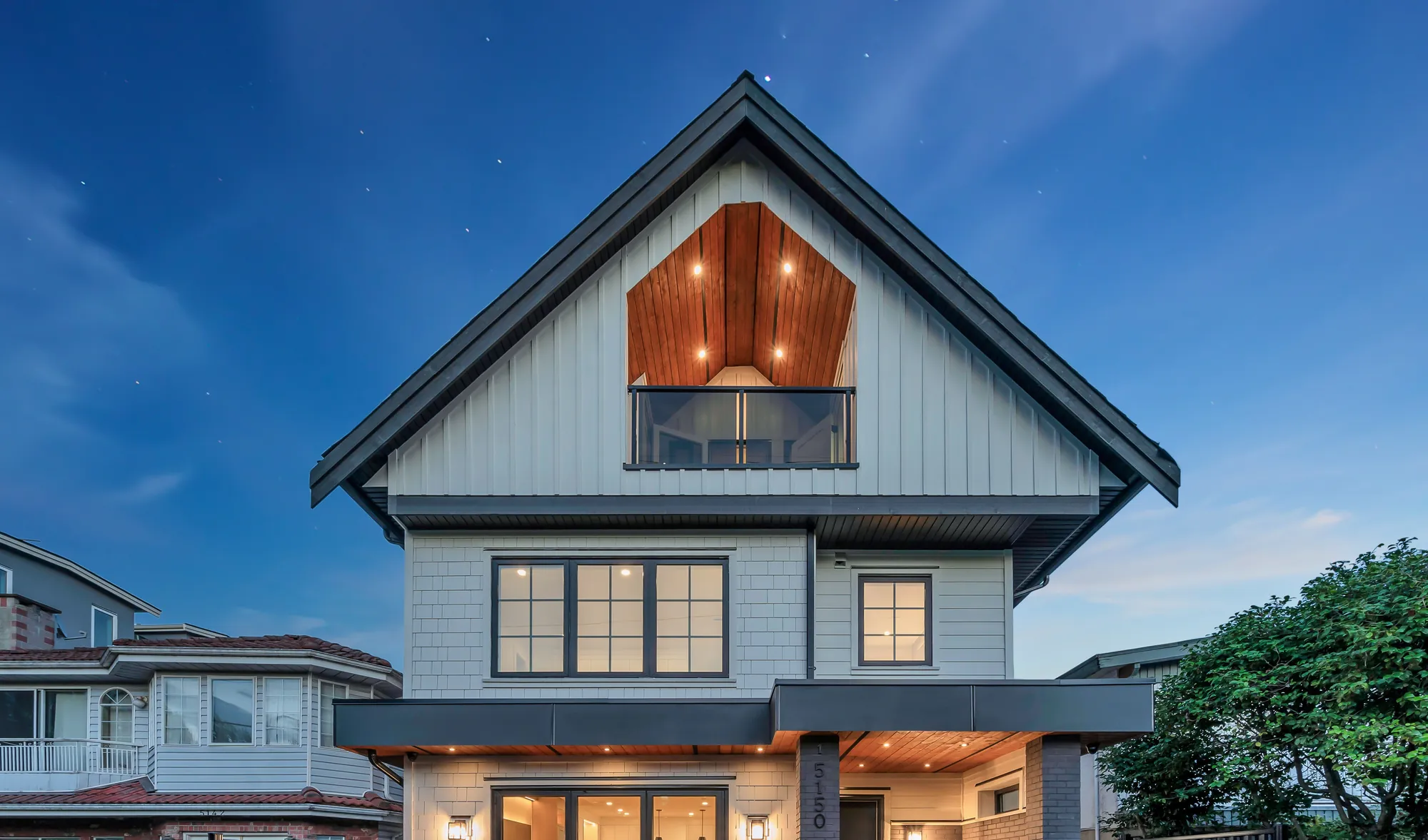 1-5150 Spencer Street at dusk: a new board-and-batten house with dark trim, its windows lit from inside