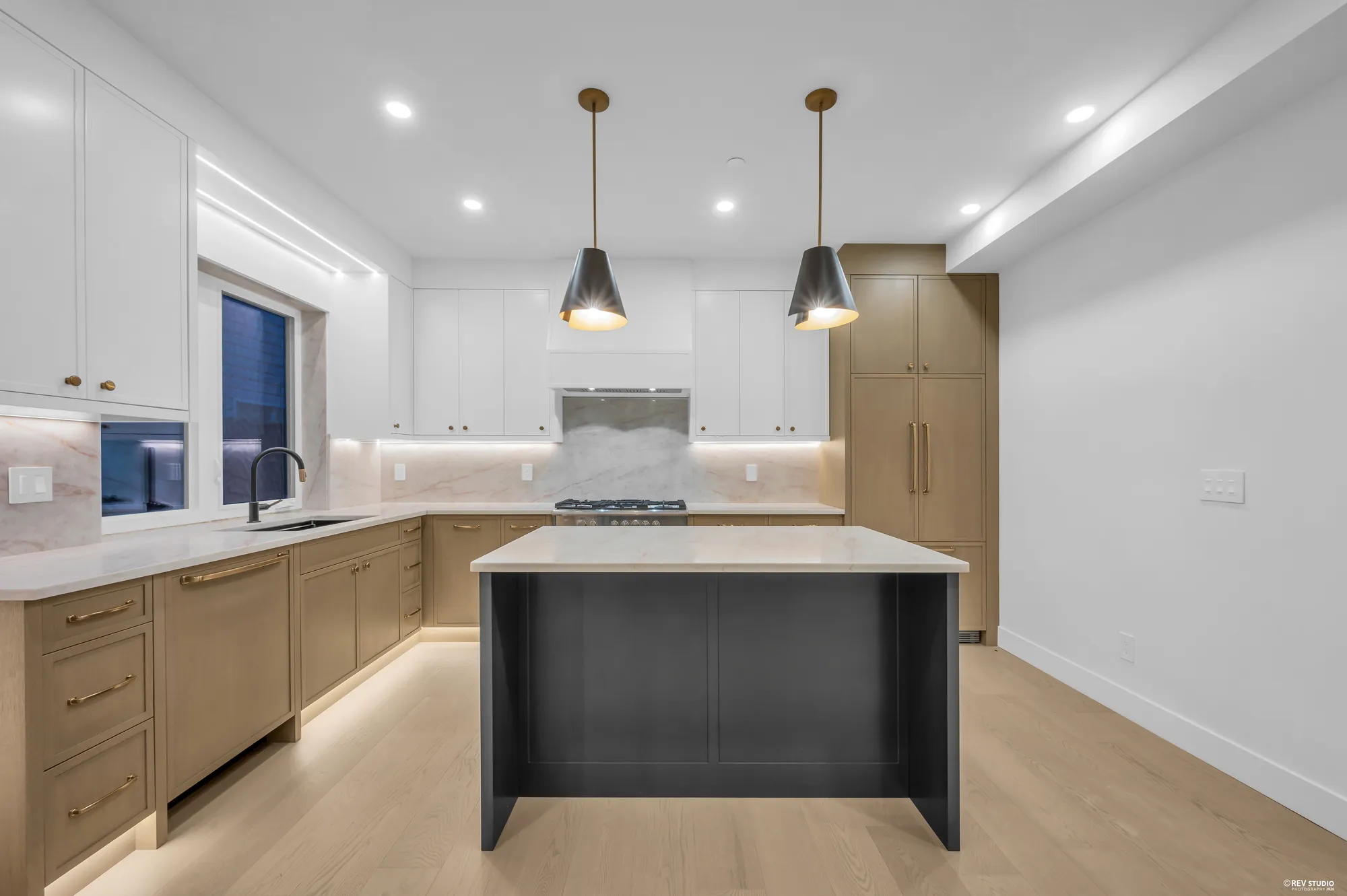 Kitchen with a black island, stone counters and pale oak cabinetry