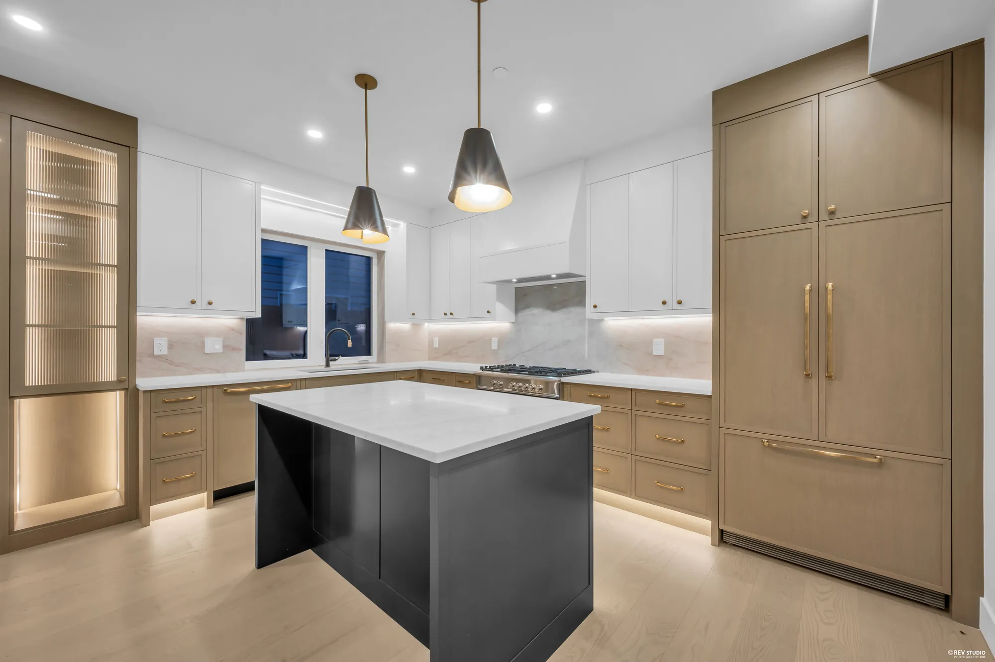 Kitchen with brass pendants above the island and a panelled fridge